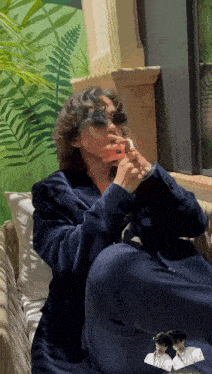 a man in a suit is sitting on a couch and smoking a cigarette