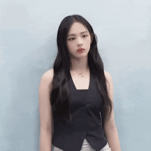 a woman with long black hair wearing a black vest
