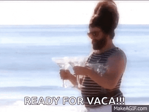 a man with a beard is standing on a beach holding a martini glass and a bag of food .
