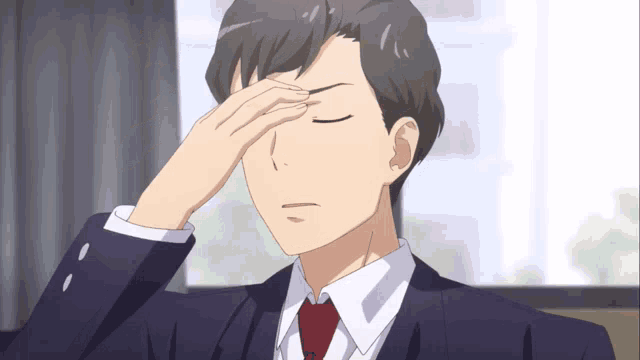 a man in a suit and tie covering his face with his hand