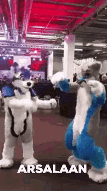 two furry costumes are dancing in a room with the word arsalaan in the corner .