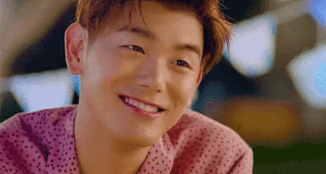 a young man in a pink shirt is smiling .