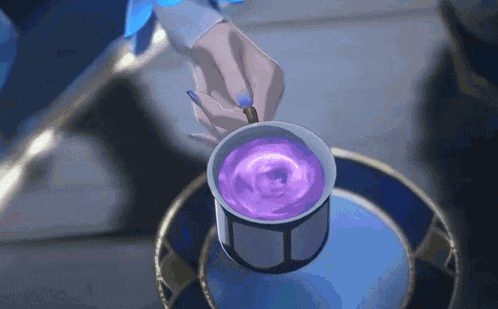 a person is holding a cup of purple liquid with a spoon .