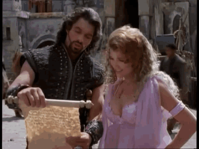 a man and a woman are standing next to each other looking at a scroll