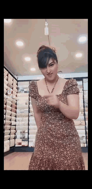 a woman in a leopard print dress is standing in front of a wall covered in wallpaper .
