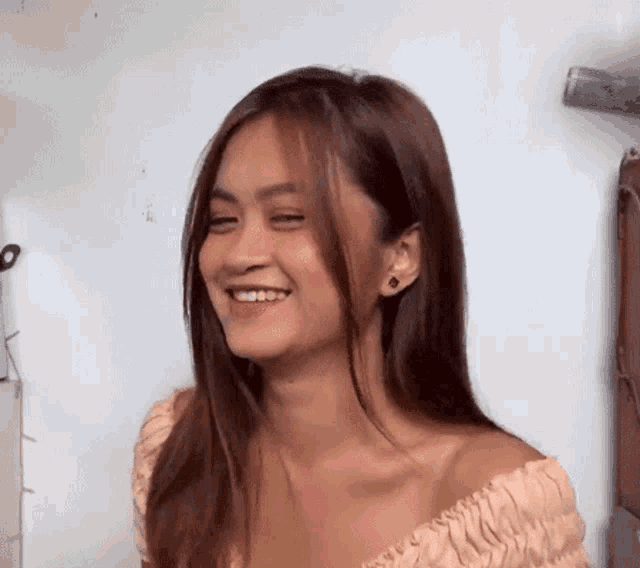 a woman with long brown hair is smiling and wearing earrings