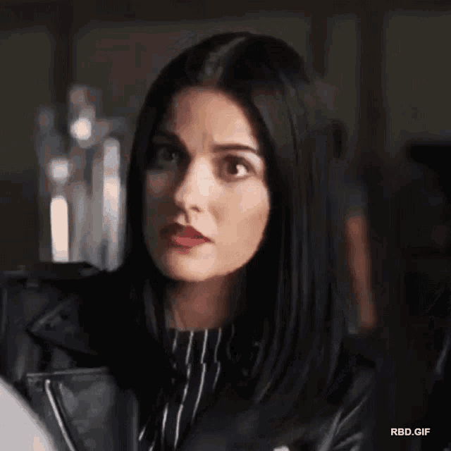 a woman is wearing a black leather jacket and a striped shirt .