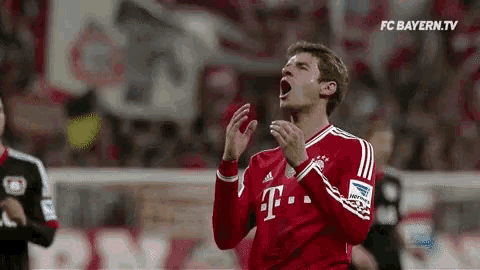 a soccer player wearing a red t-mobile jersey is clapping his hands during a game .