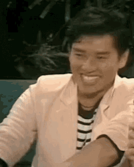 a man in a pink jacket and striped shirt is smiling and laughing .