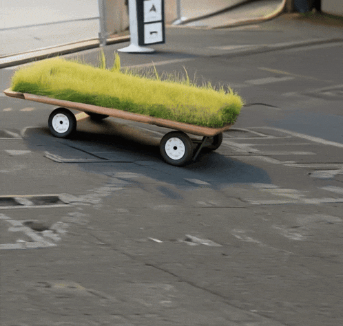 a wagon with grass on it is driving down the street