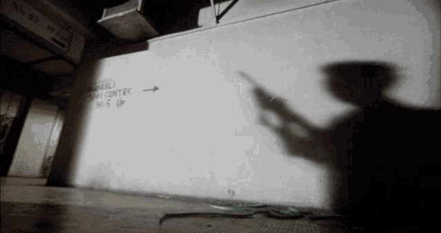 a shadow of a person holding a gun is cast on a wall that says space centre on it