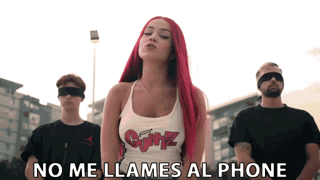 a woman with red hair and a shirt that says cumz stands in front of two men