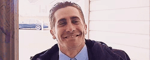 a man in a suit and tie is smiling with his eyes closed .