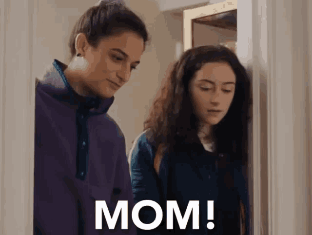 two women are standing next to each other in a room and one of them is talking to the other .
