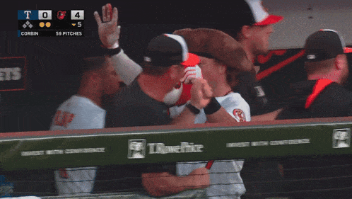 a baseball player wearing a pirate hat high fives another player in a dugout