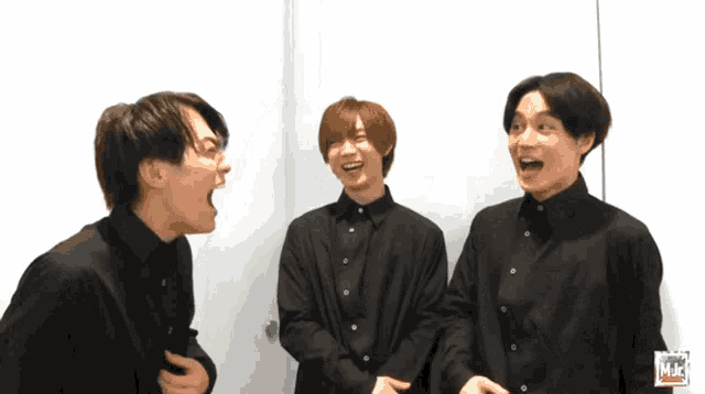 three men in black shirts are laughing and one of them has a mjc logo on his shirt