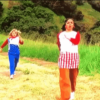 a woman in a red white and blue plaid skirt stands in a grassy field
