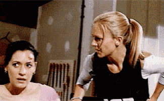 two women are standing next to each other in a room looking at each other