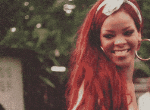 a woman with red hair and hoop earrings smiles for the camera