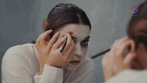 a woman is applying makeup in front of a mirror with star written on the bottom