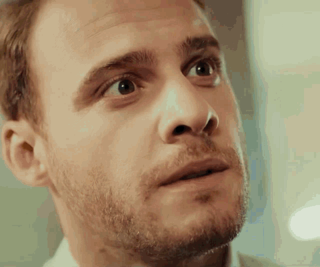 a close up of a man 's face with a beard looking up at something