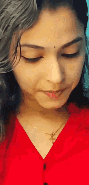a close up of a woman wearing a red shirt and a gold necklace