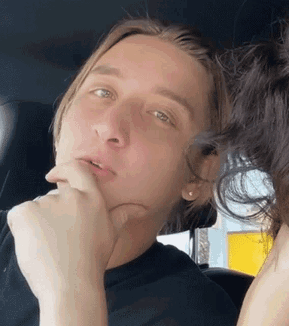 a man sitting in a car with his hand to his chin