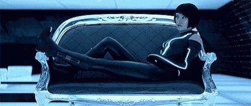 a woman in a futuristic outfit is laying on a couch with her legs crossed