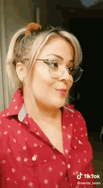 a woman wearing glasses and a red shirt is looking at the camera .