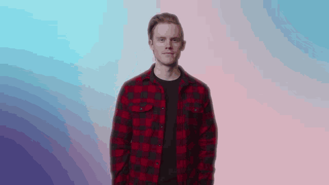 a man in a red and black plaid shirt is standing in front of a pink and blue background