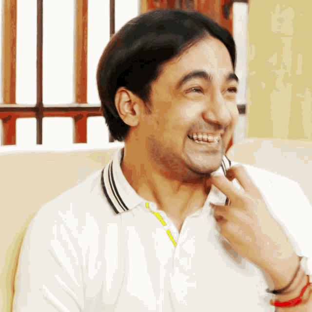 a man in a white shirt with a yellow stripe on the collar smiles