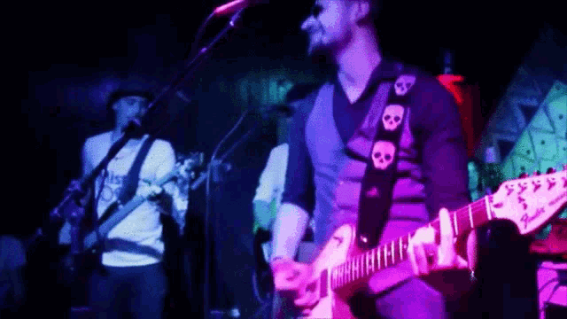 a man playing a guitar with a fender logo on it