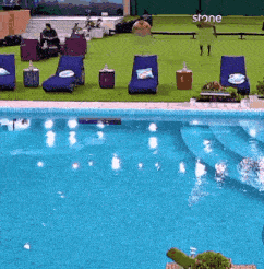 a large swimming pool surrounded by lawn chairs and tables