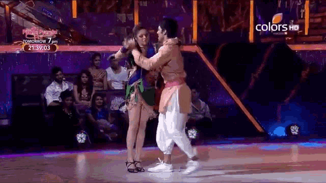 a man and a woman are dancing on a stage with a sign that says colors hd on it