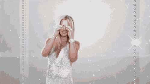 a woman in a white dress is smiling while holding her hair .
