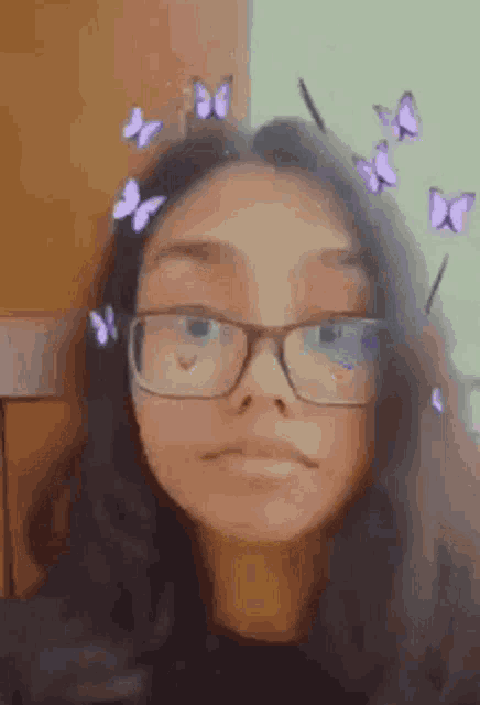a girl wearing glasses and purple butterflies on her head is making a funny face .