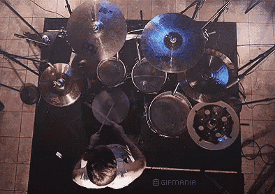 an aerial view of a man playing drums with the words gifmania on the bottom right