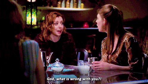 a woman sitting at a table talking to another woman who says god what is wrong with you ?