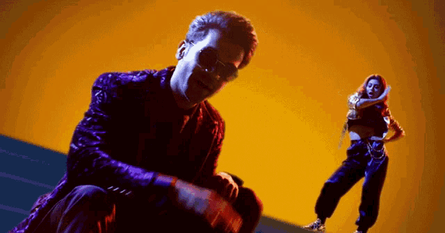 a man in a purple jacket is kneeling down next to a woman in a black outfit