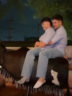 a man and a woman are sitting on a couch with their arms around each other .