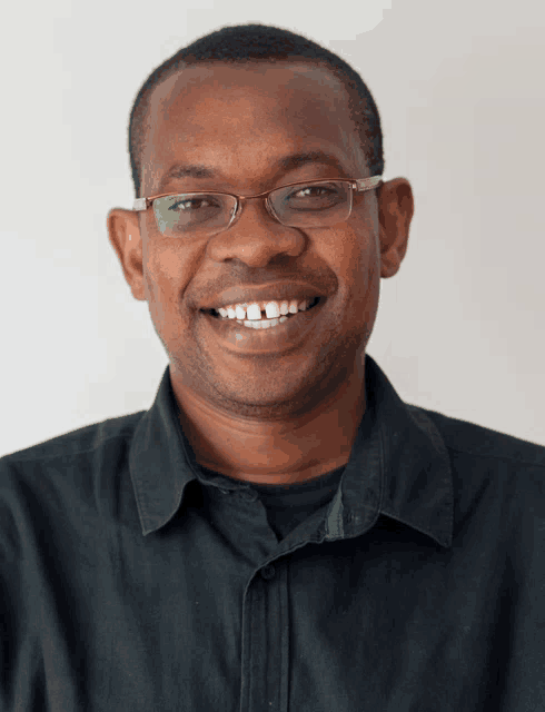 a man wearing glasses and a black shirt smiles at the camera