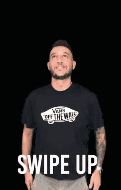 a man wearing a black vans off the wall shirt holds his hands up in the air