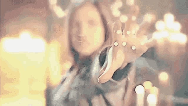 a woman is covering her face with her hands while standing in front of a window .