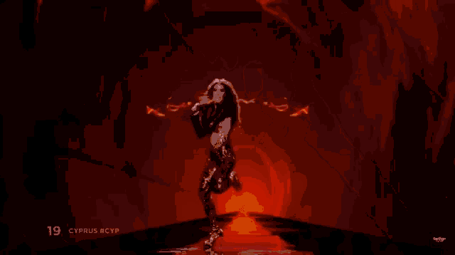 a woman in a bikini is dancing in front of a wall of fire .