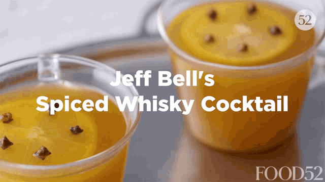 two cups of jeff bell 's spiced whisky cocktail with lemon slices and cloves