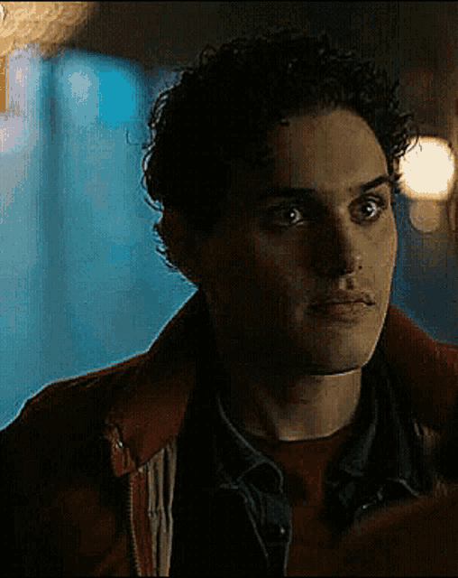 a man with curly hair is wearing a red jacket and a red shirt