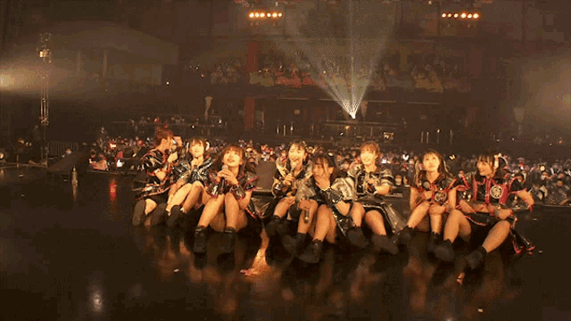a group of girls are sitting on a stage with microphones in their hands