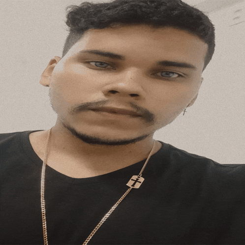 a young man wearing a black shirt and a gold chain with a cross on it