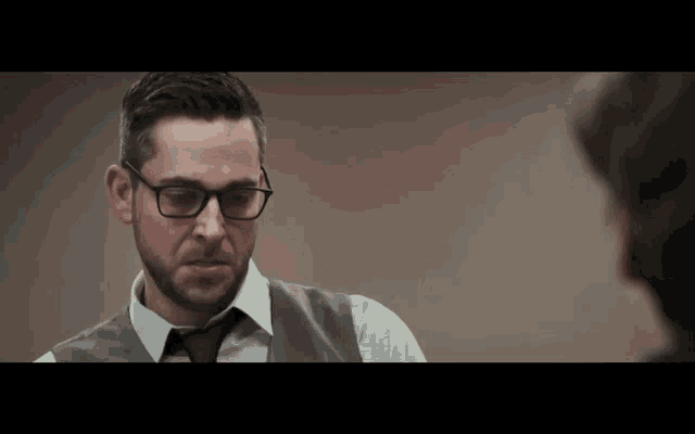 a man wearing glasses and a vest and tie
