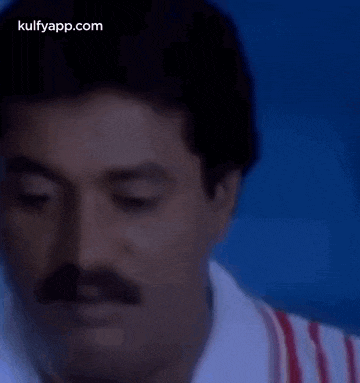 a close up of a man 's face with a mustache and a white shirt .